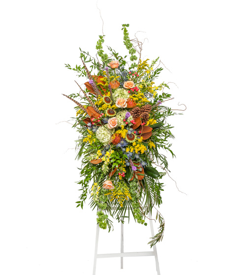 The Great Outdoors Funeral Stand with peach roses, hydrangeas, protea, feathers, pinecones, and rustic greenery on a white easel