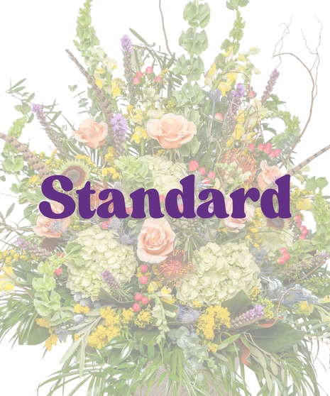 The Great Outdoors Urn Arrangement with peach roses, green hydrangeas, protea, feathers, and rustic greenery in a tall urn