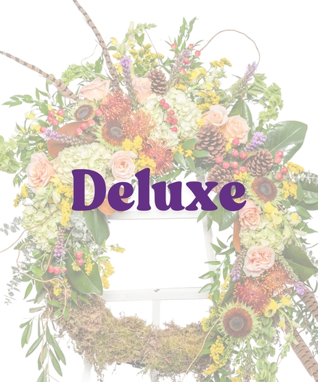 The Great Outdoors Wreath Stand with moss base, peach roses, hydrangeas, pinecones, and pheasant feathers on a white easel