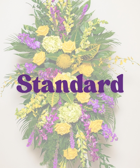 Tiger Pride Funeral Stand with yellow roses, purple orchids, snapdragons, green hydrangeas, and tropical foliage on a white easel