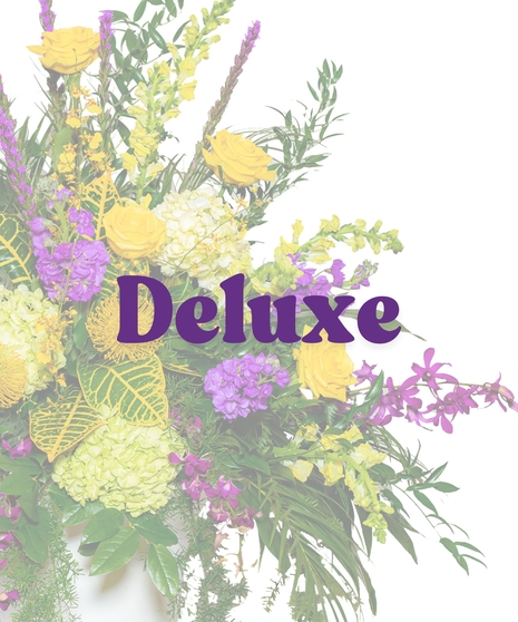 Tiger Pride Urn Funeral Arrangement with yellow roses, purple orchids, green hydrangeas, and cascading greenery in a white urn