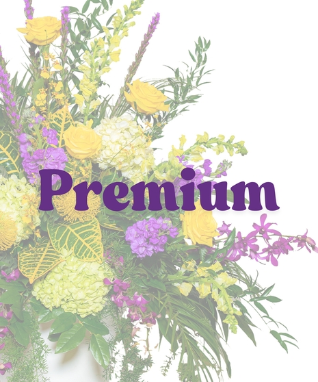 Tiger Pride Urn Funeral Arrangement with yellow roses, purple orchids, green hydrangeas, and cascading greenery in a white urn