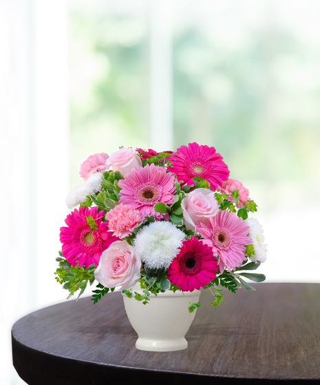Upsy Daisy flower arrangement with hot pink gerbera daisies, pale pink roses, white mums, and carnations in a white pedestal vase.
