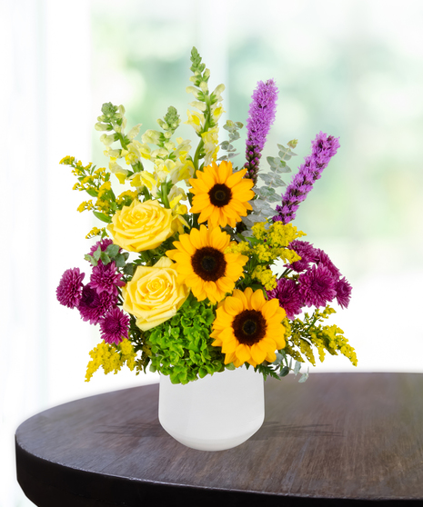 Urban Tiger flower arrangement with sunflowers, yellow roses, purple mums, green hydrangeas, and liatris in a white vase