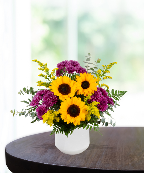 Urban Tiger flower arrangement with sunflowers, yellow roses, purple mums, green hydrangeas, and liatris in a white vase
