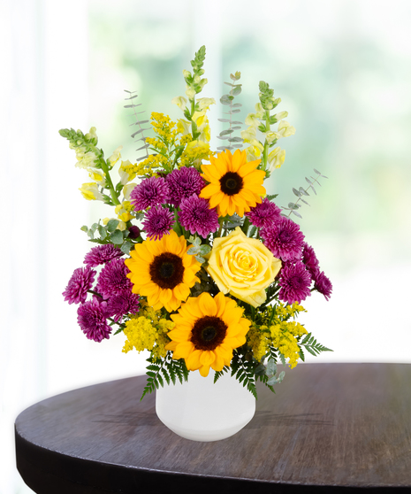 Urban Tiger flower arrangement with sunflowers, yellow roses, purple mums, green hydrangeas, and liatris in a white vase