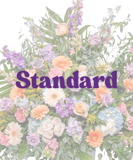 Pastel urn flower arrangement with roses, gerberas, hydrangeas, and spring blooms in a classic pedestal vase from Billy Heroman’s in Baton Rouge