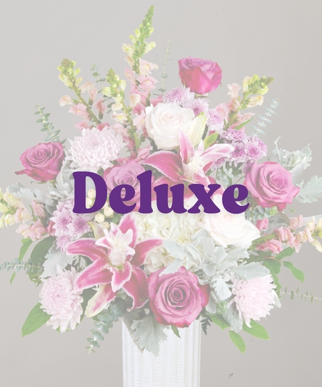 Viola flower arrangement with rose lilies, purple roses, snapdragons, hydrangeas, and eucalyptus in a tall white vase