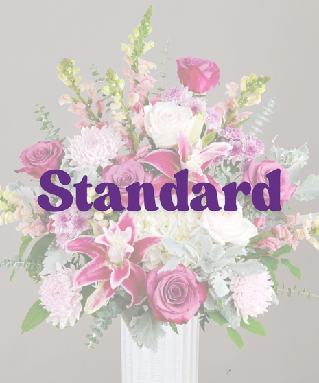 Viola flower arrangement with rose lilies, purple roses, snapdragons, hydrangeas, and eucalyptus in a tall white vase