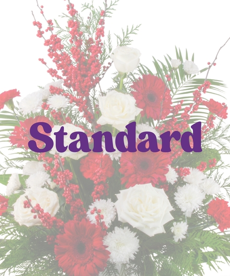 Winter Berry funeral floor arrangement with white roses, red gerberas, red carnations, white chrysanthemums, red berries, and seasonal winter greenery in a white container.