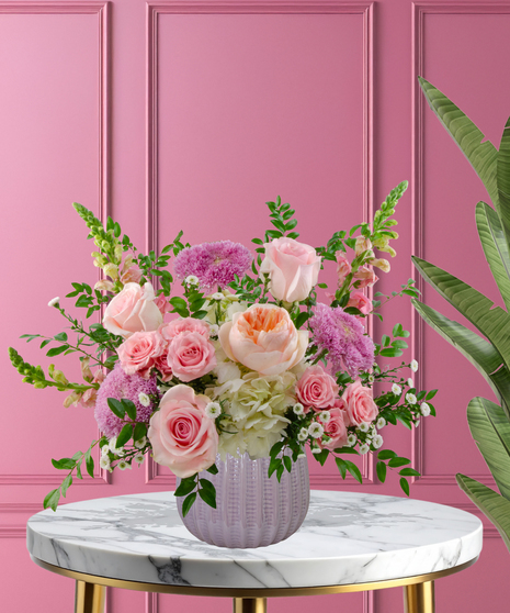 Wild About You stunning Valentine's arrangement with peach garden roses, pink roses, white hydrangeas, and pink snapdragons in a lavender ribbed vase.