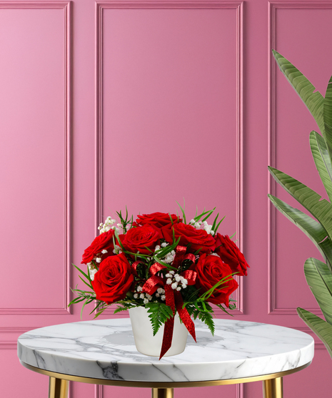 With All My Heart exclusive Valentine's flower arrangement with red roses, white baby's breath, and a red glitter ribbon in a white ceramic vase.
