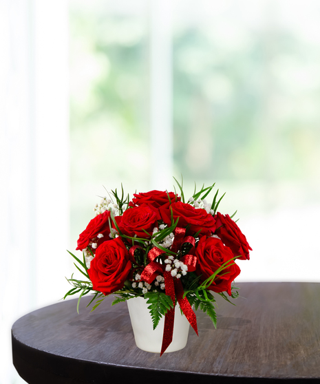 With All My Heart exclusive Valentine's flower arrangement with red roses, white baby's breath, and a red glitter ribbon in a white ceramic vase.