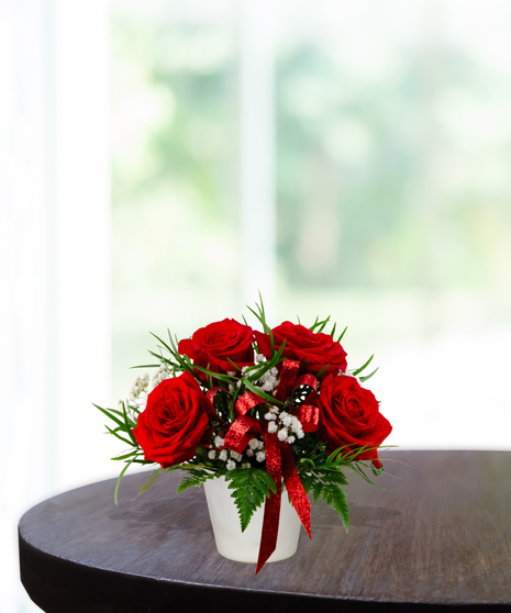 With All My Heart exclusive Valentine's flower arrangement with red roses, white baby's breath, and a red glitter ribbon in a white ceramic vase.