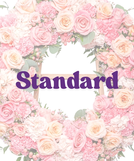 Circular funeral wreath with peach and pink roses, carnations, and hydrangea on a stand