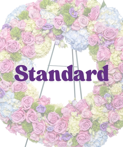 Spring funeral wreath with pastel pink, lavender, blue, and green florals on easel by Billy Heroman’s in Baton Rouge, LA