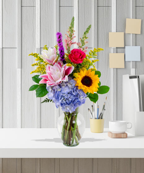 Brighten Her Day flower arrangement with sunflowers, hydrangeas, roses, lilies, and liatris in a glass vase – Admin Week appreciation bouquet.