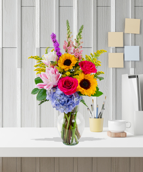 Brighten Her Day flower arrangement with sunflowers, hydrangeas, roses, lilies, and liatris in a glass vase – Admin Week appreciation bouquet.