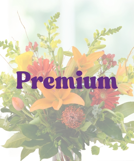 Orange Crush flower arrangement featuring orange lilies, red gerberas, yellow snapdragons, and tropical greenery in a glass vase